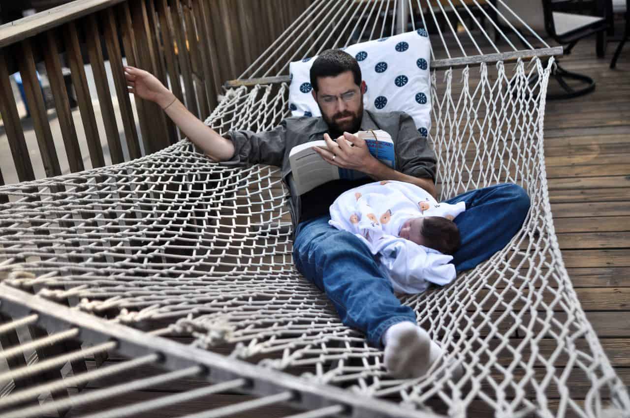 man laying in hammock with baby
