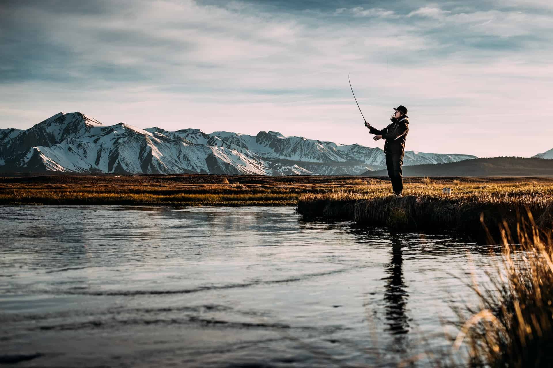 woman fly fishing with mountians in the background