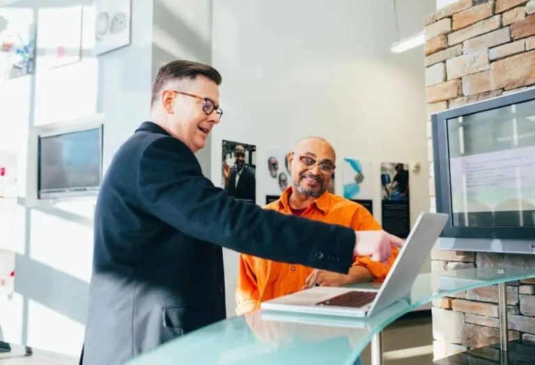 smiling people using a laptop