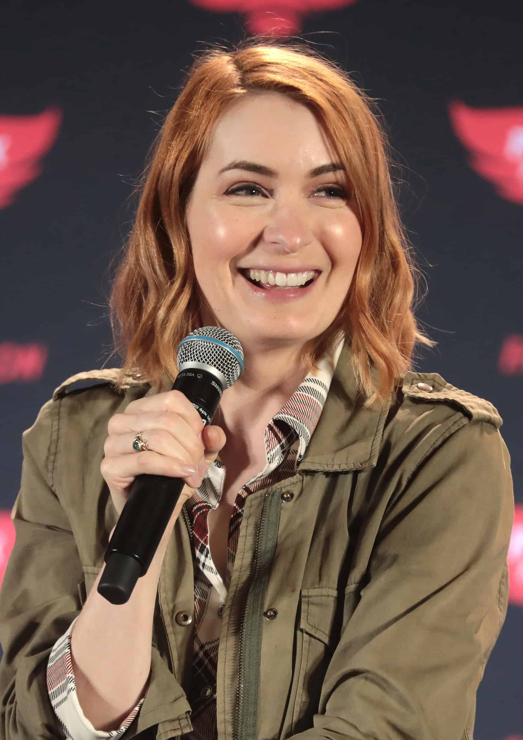 A woman in her 40s, immersed in gaming, sits in a cozy, cluttered room. Felicia Day