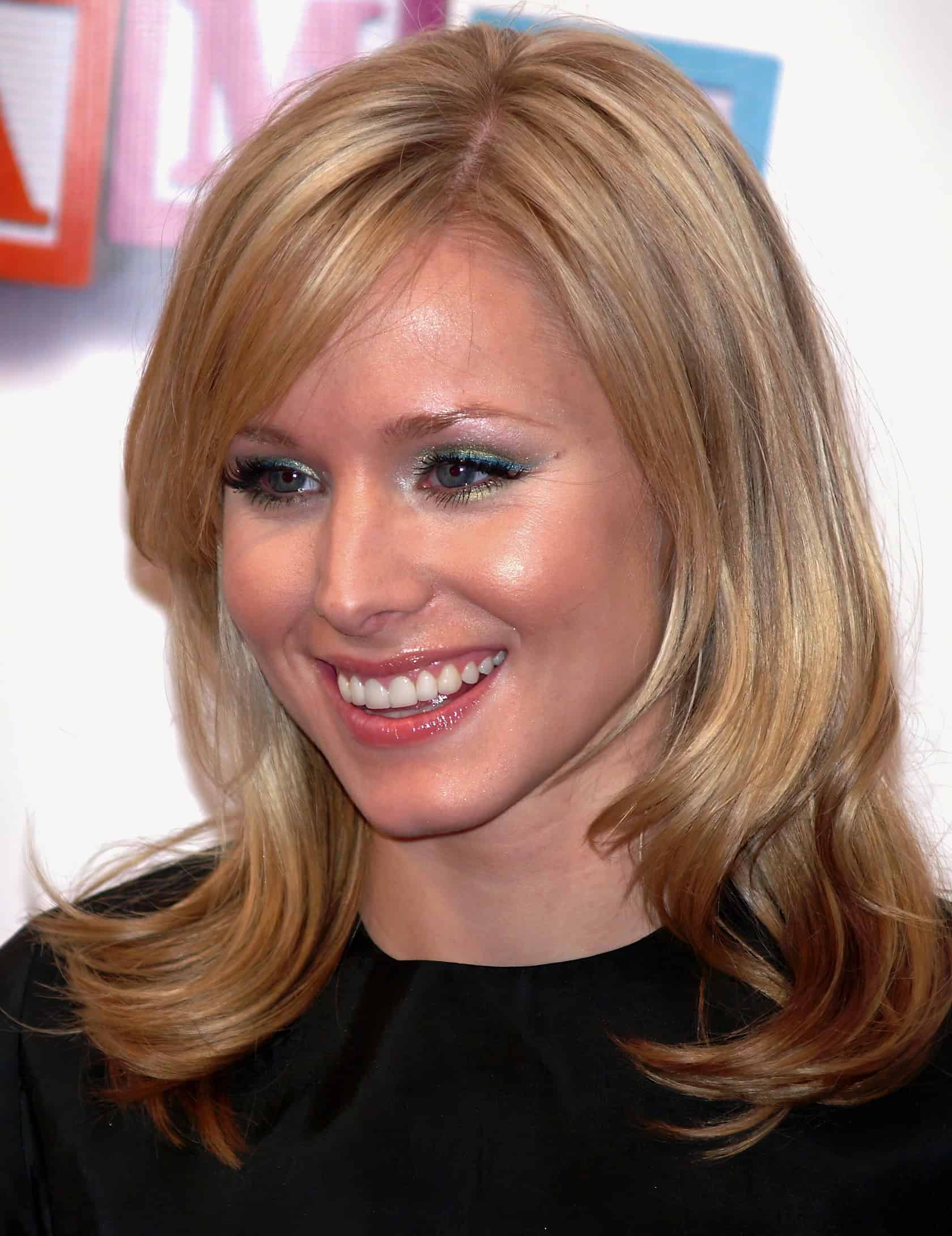 Kristen Bell at Comic-Con, wearing a casual blouse, surrounded by fans in cosplay costumes. Kristen Bell