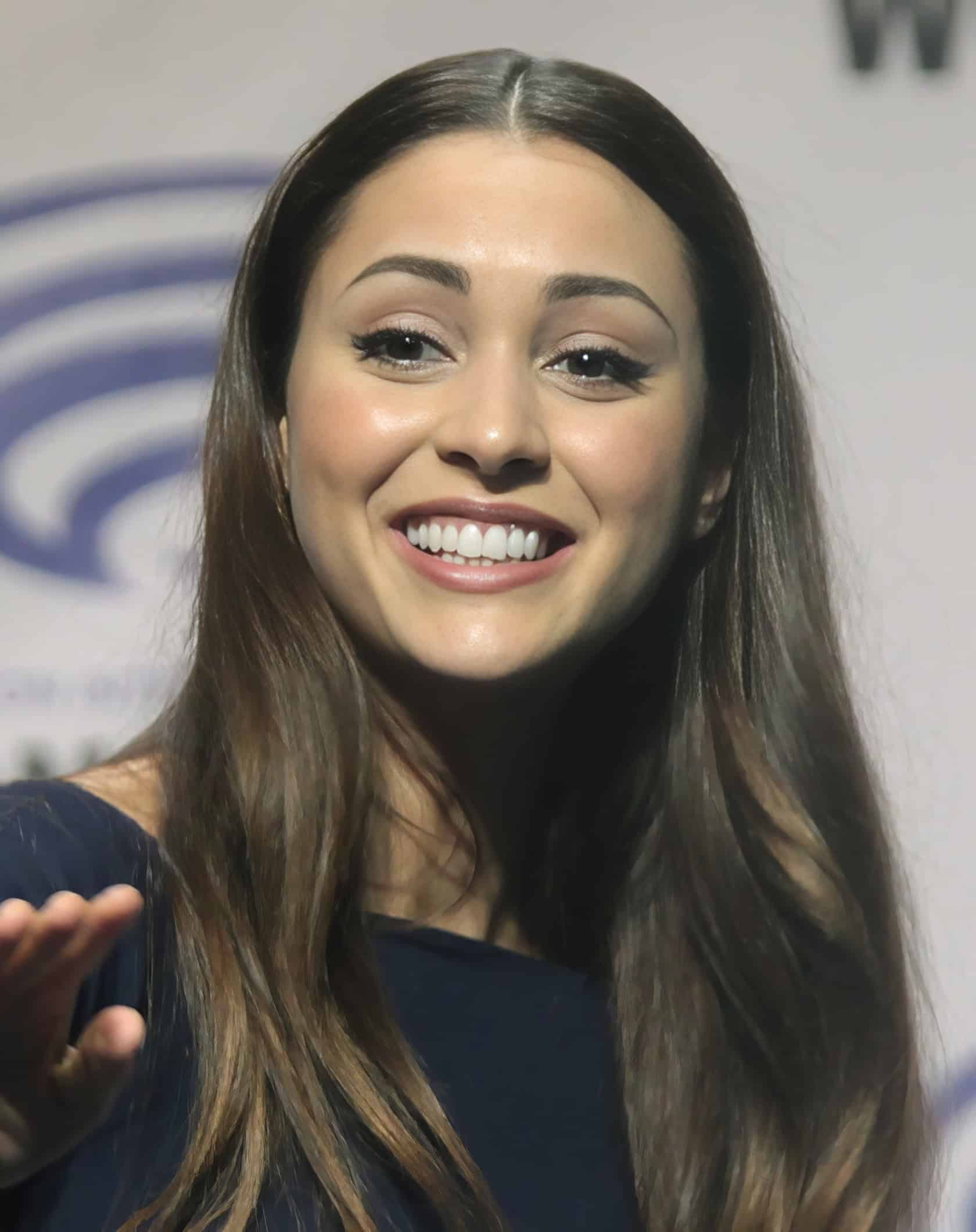 A woman stands confidently in a spaceship corridor, wearing workout gear and exuding determination. Lindsey Morgan