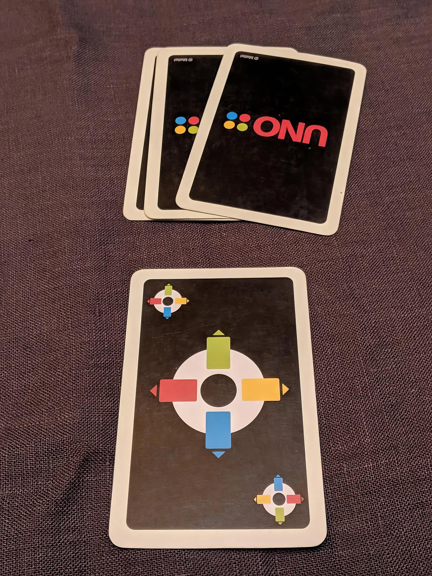 Two men play Uno Mod at a weathered wooden table in a softly lit room. Uno Mod Game 3