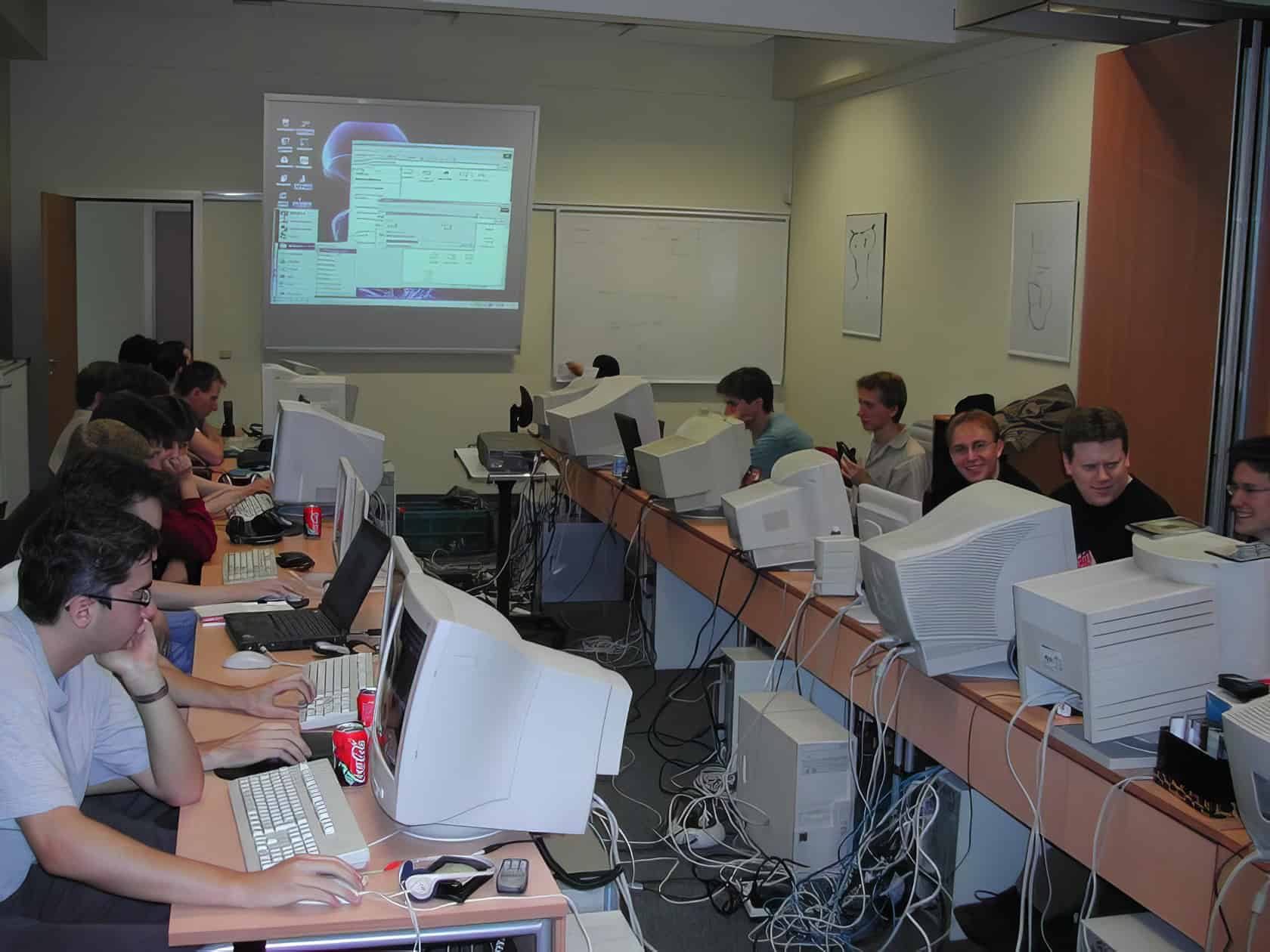 A gamer adjusts settings on a multi-monitor setup in a cozy gaming space, surrounded by peripherals and a gaming chair. What Do You Need for LAN Party Fun 11