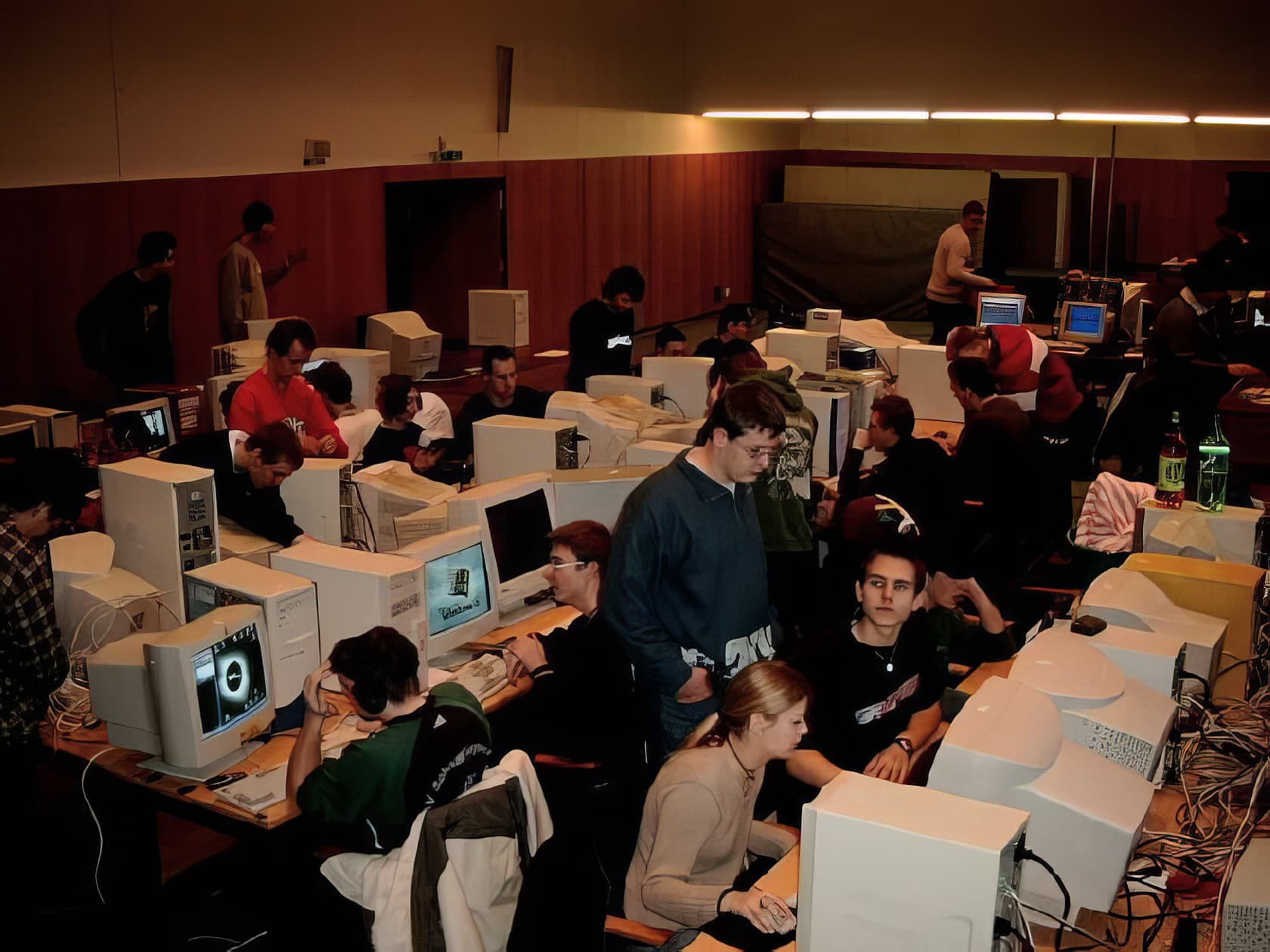 A group of five young adults engages intensely in a gaming session around a cluttered table filled with gaming equipment. What Do You Need for LAN Party Fun 13