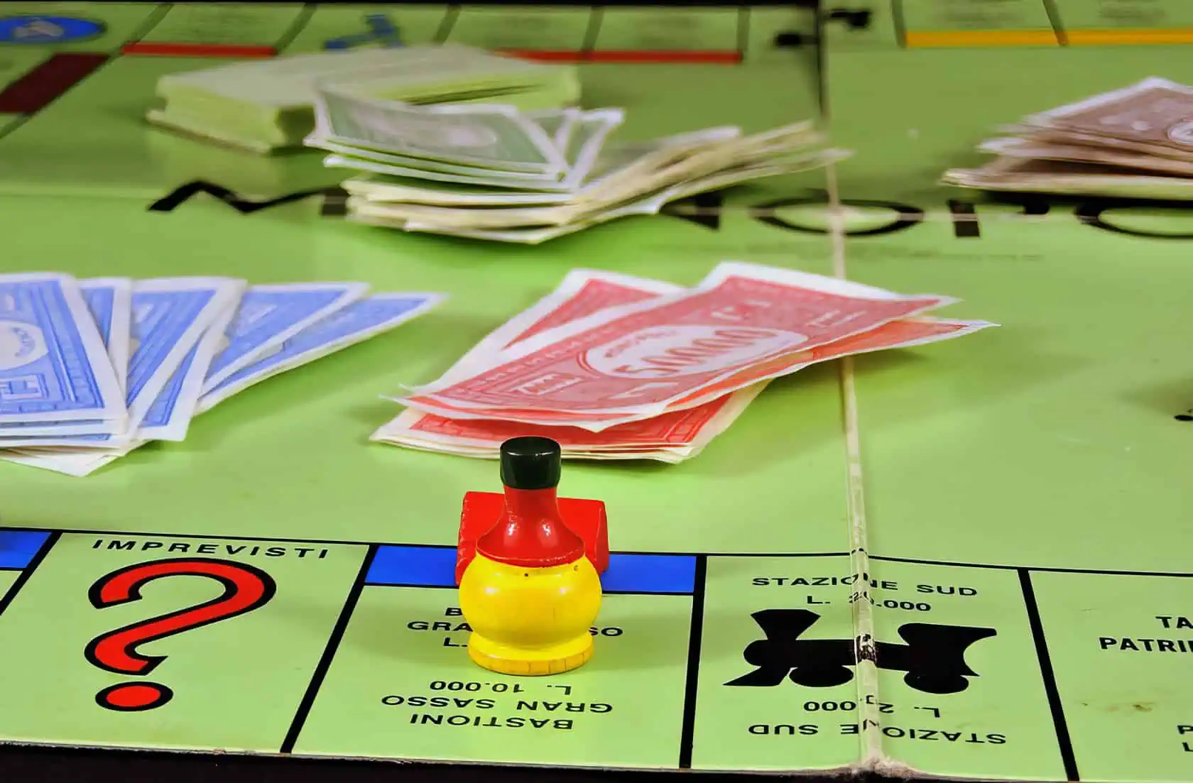 A person plays Monopoly, adjusting a house on a well-worn game board with arranged property groups. When Can You Buy Houses in Monopoly 2