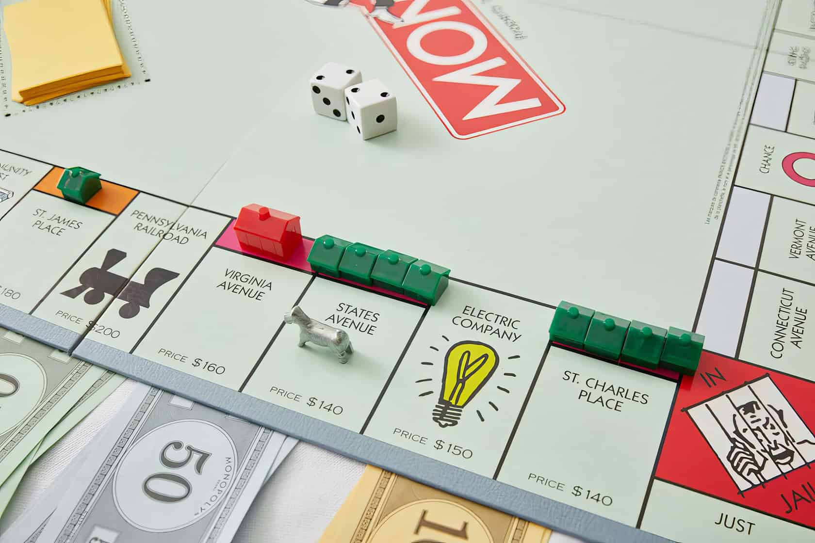 A woman meticulously arranges model houses on a well-worn board game in a cozy, lived-in room. When Can You Buy Houses in Monopoly 4