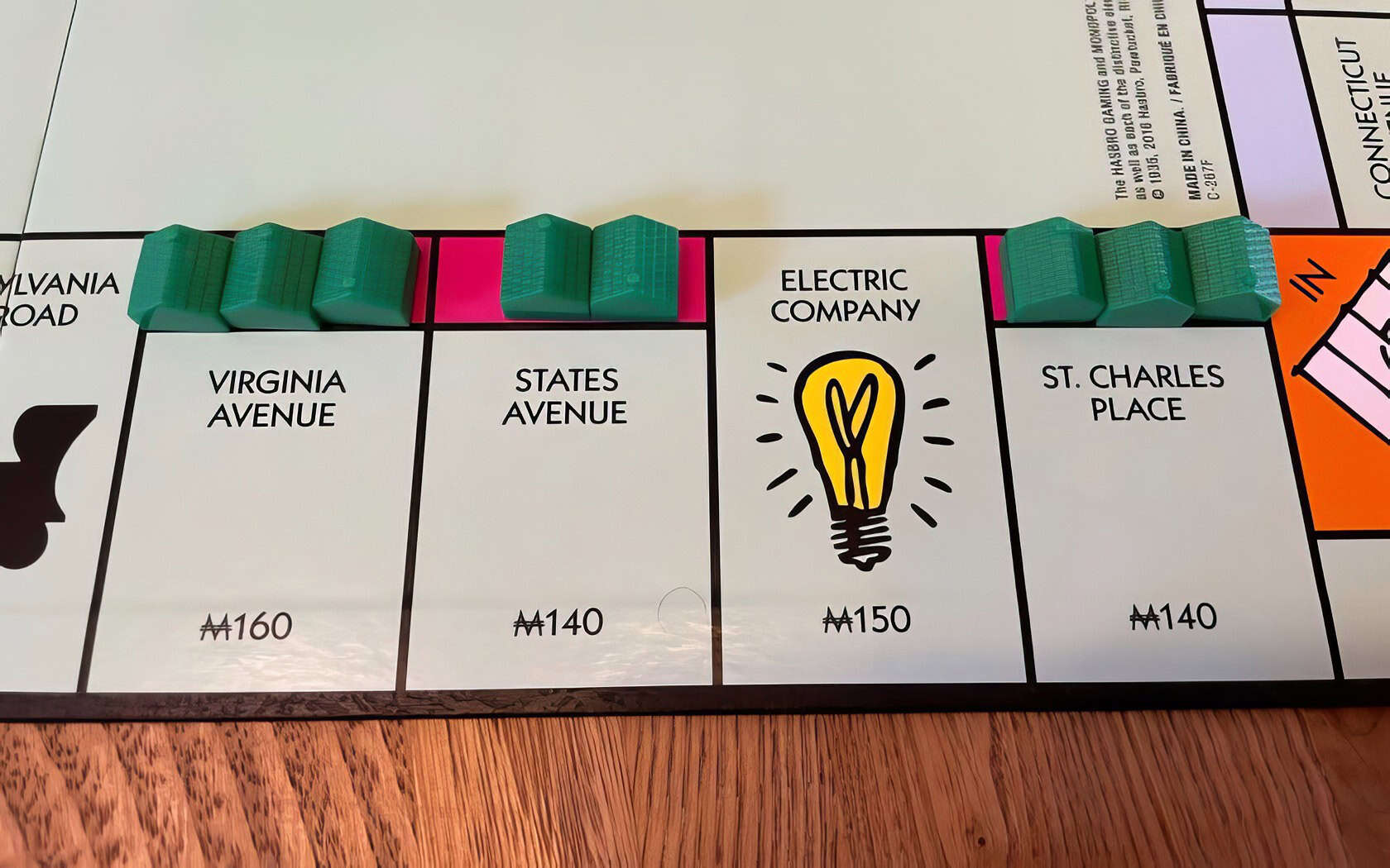 A woman concentrates while placing a wooden token on a vibrant Monopoly board in a cozy living room. When Can You Buy Houses in Monopoly 5