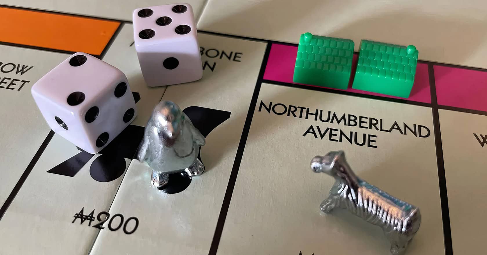 A close-up of a Monopoly board game showcases organized Title Deed cards on a weathered oak table with relaxed hands nearby. When Can You Buy Houses in Monopoly 6