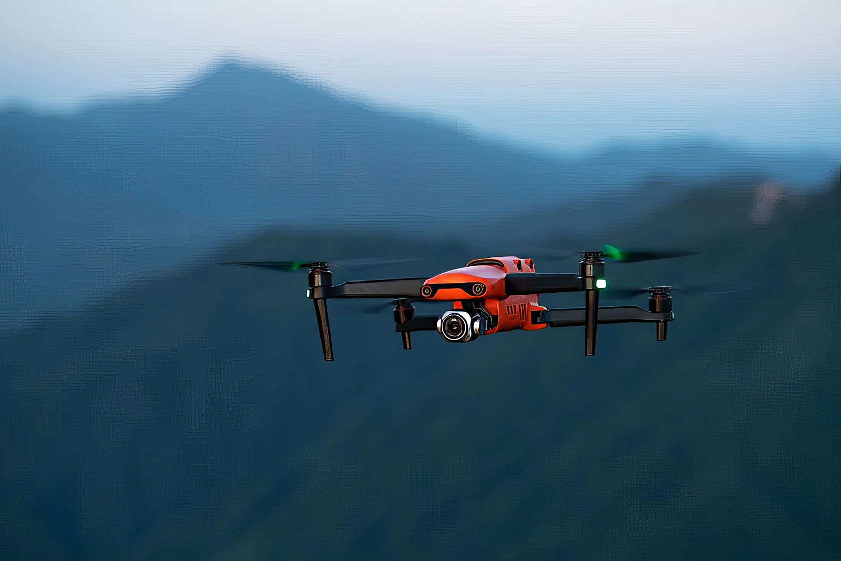 A casually dressed man in a forest is focused on his drone controller in a natural, unposed moment. High-speed racing drone flying over water with scenic mountain background, showcasing advanced drone technology and aerial photography capabilities for hobbyists and professionals.