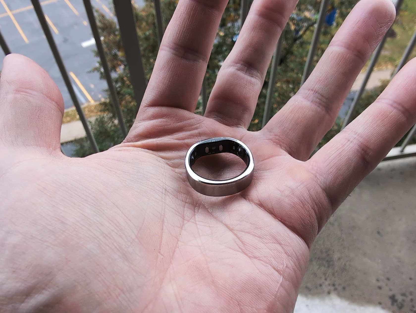 RingConn Gen 2 Air Review: 10 Reasons to Buy or Skip in 2025 2 Ring on person's hand outdoors with blurred background of trees and parking lot.