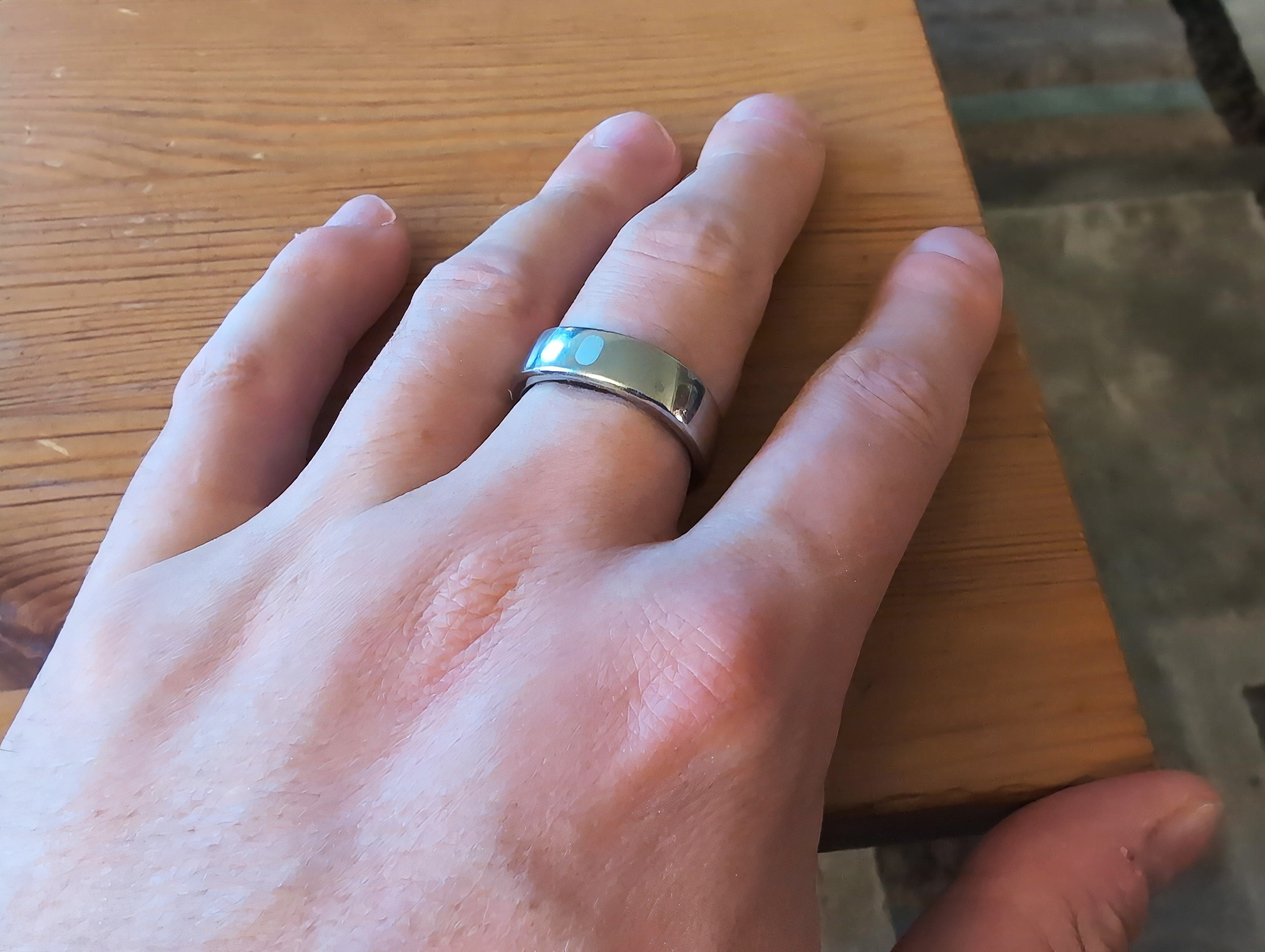 RingConn Gen 2 Air Review: 10 Reasons to Buy or Skip in 2025 4 Sterling silver band ring on a person's finger resting on wooden surface.