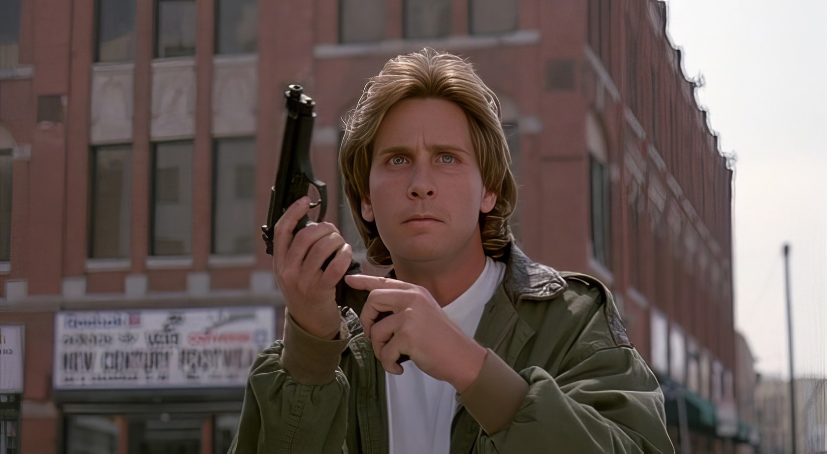 The Legacy of Loaded Weapon 2: A Deep Dive Into the Unmade Sequel 3 Gun held up by young man on city street, tense expression, urban background with brick buildings, drama, action scene, movie shot, intense moment, cinematic urban setting, thriller vibe, character in focus.