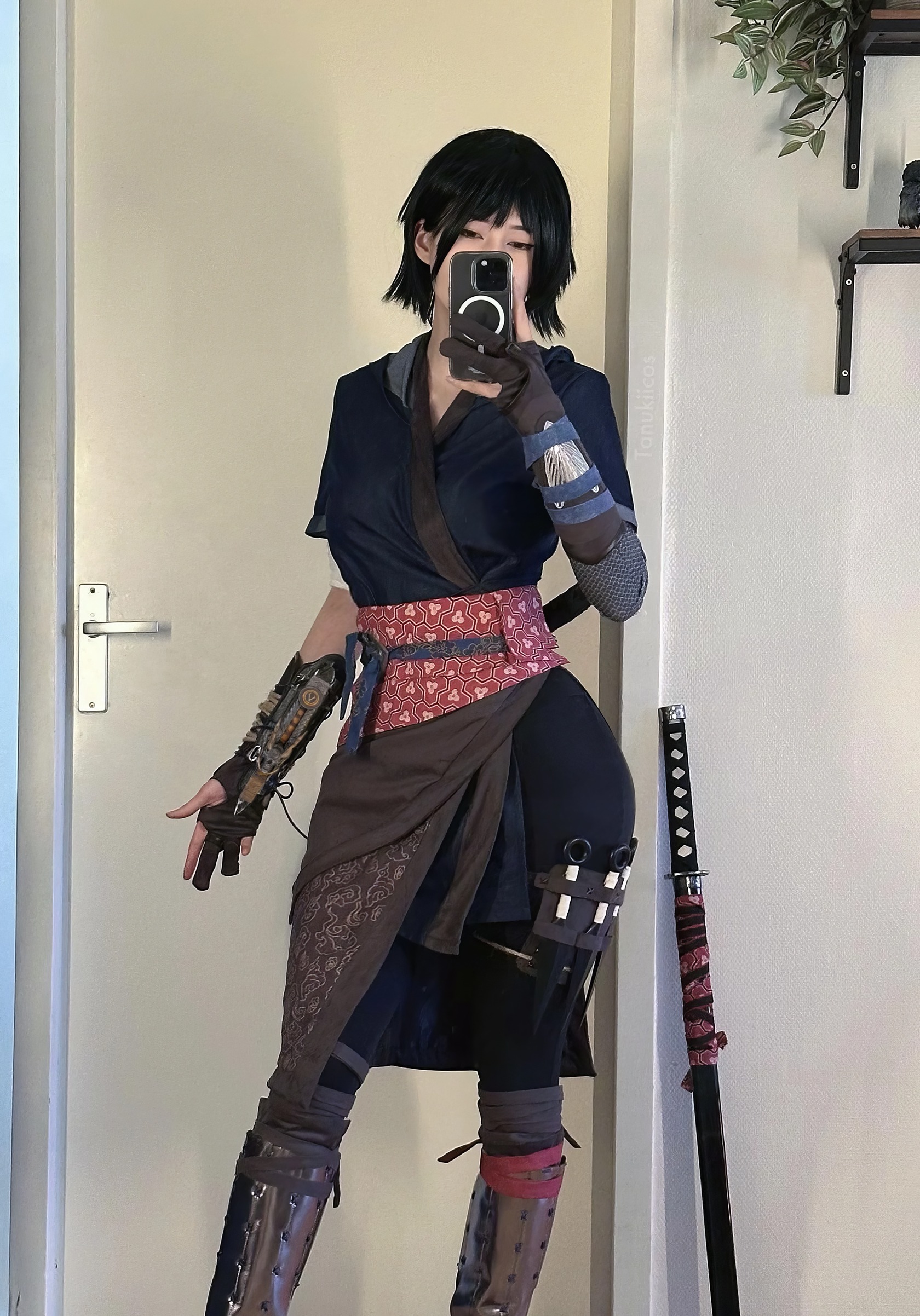 Assassin's Creed Hot Cosplay: 20+ Character Costumes & DIY Tips 19 Black-haired woman cosplaying as a fierce warrior in intricate costume, taking mirror selfie indoors, with katana sword and detailed armor elements, showcasing cosplay craftsmanship and anime-inspired style.