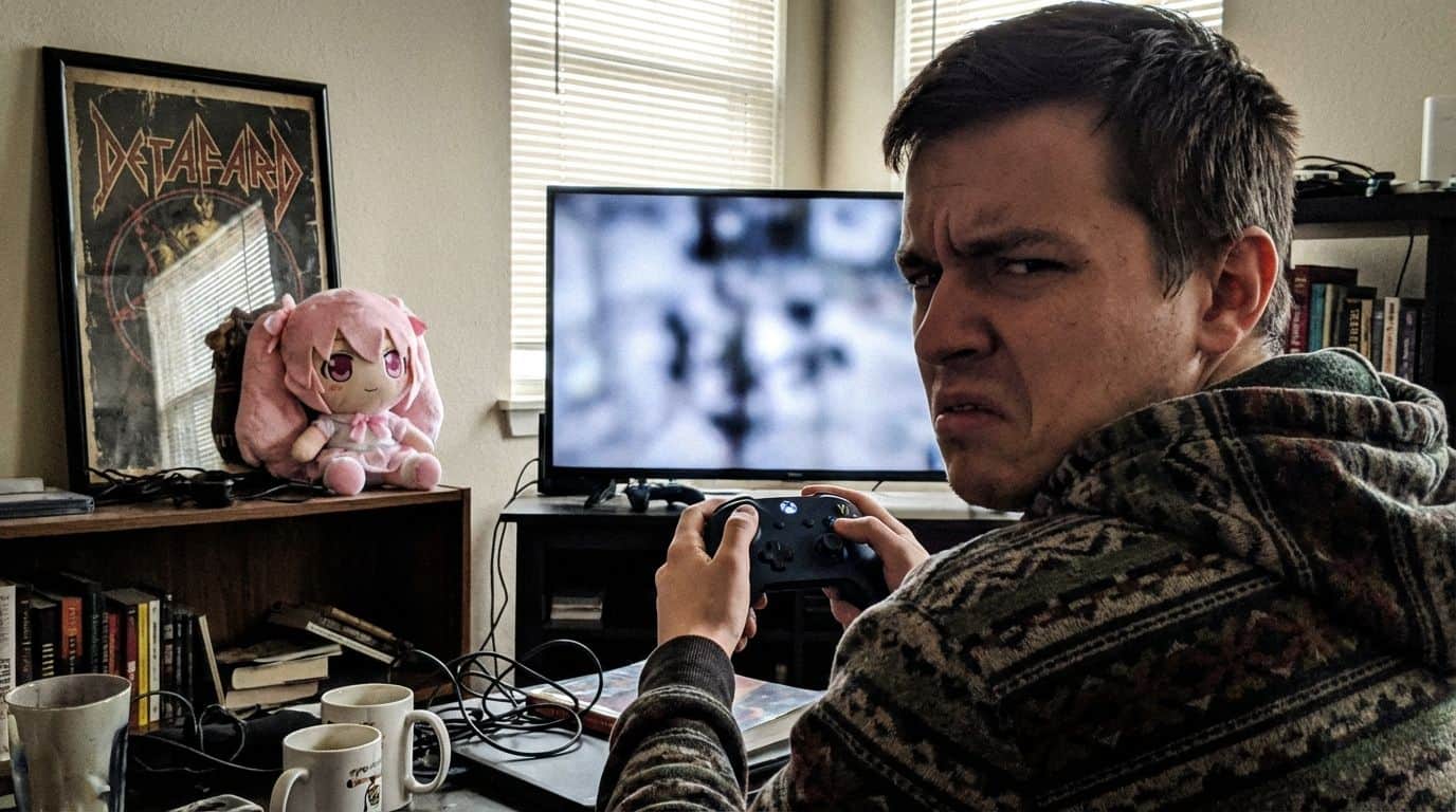 Enjoy gaming with a frustrated young man holding an Xbox controller, surrounded by gaming accessories, in a cozy room with a TV, books, and a plush anime doll on the shelf.