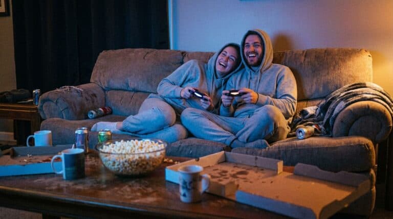 Enjoying a cozy movie night with friends, playing video games, surrounded by snacks and drinks in a warm, inviting living room. Great for relaxing and bonding.