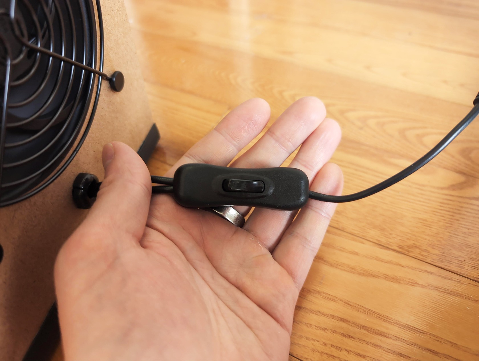 NorthBox 5X Classic Review: Stop Paying for Expensive Air Filters 4 Close-up of a hand holding a power switch connected to an air purifier, highlighting the NorthBox 5X Classic air filter for efficient air cleaning.