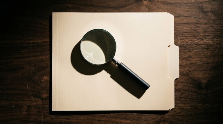 Magnifying glass placed on an open folder, symbolizing detailed review of FCRA screening procedures for legal compliance.