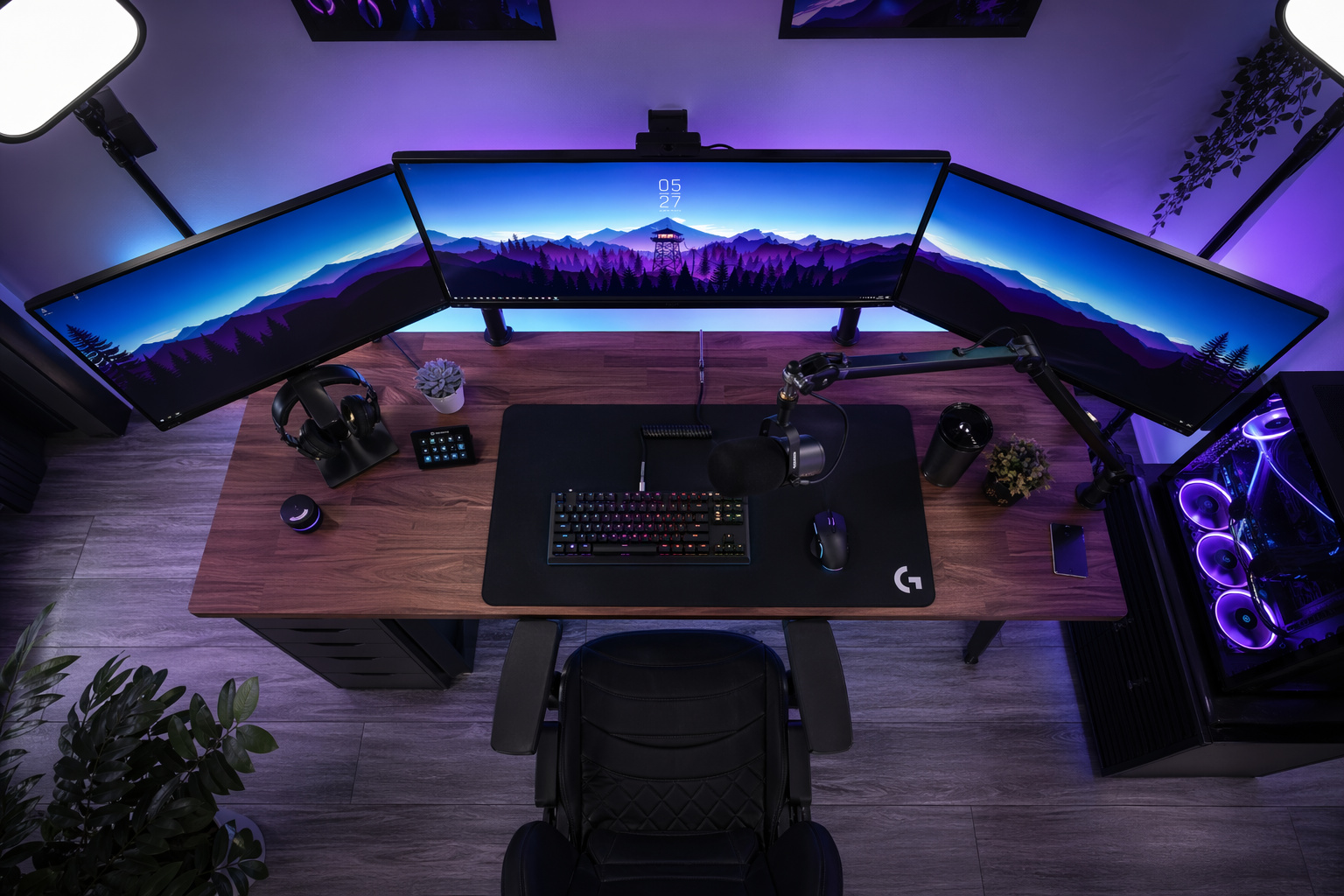 High-performance gaming desk with triple ultra-wide monitors, RGB lighting, mechanical keyboard, gaming mouse, and accessories for an immersive gaming experience.