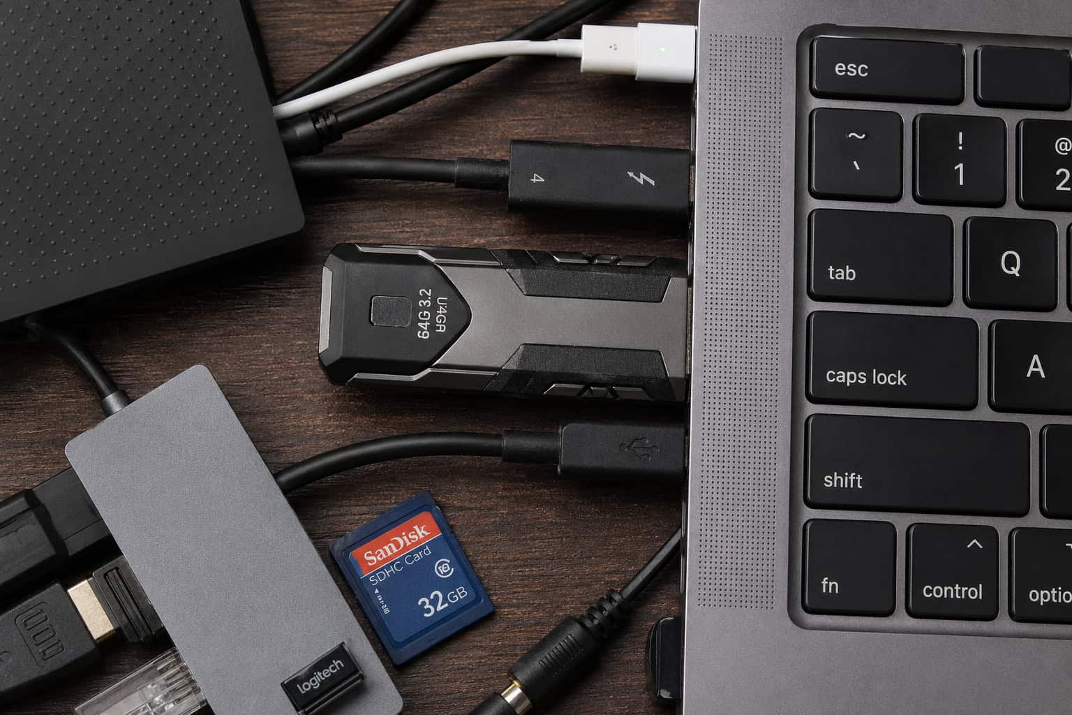 Close-up of a gaming USB flash drive connected to a laptop with various tech accessories, highlighting data storage and transfer solutions for gamers and tech enthusiasts.