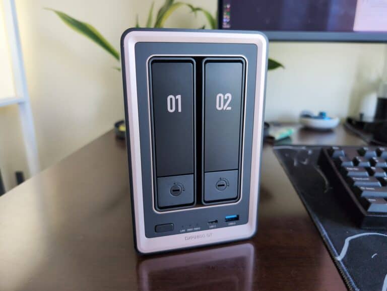 Close-up of UGREEN DXP2800 GT 2-bay NAS device on desk with computer monitor and keyboard in background.