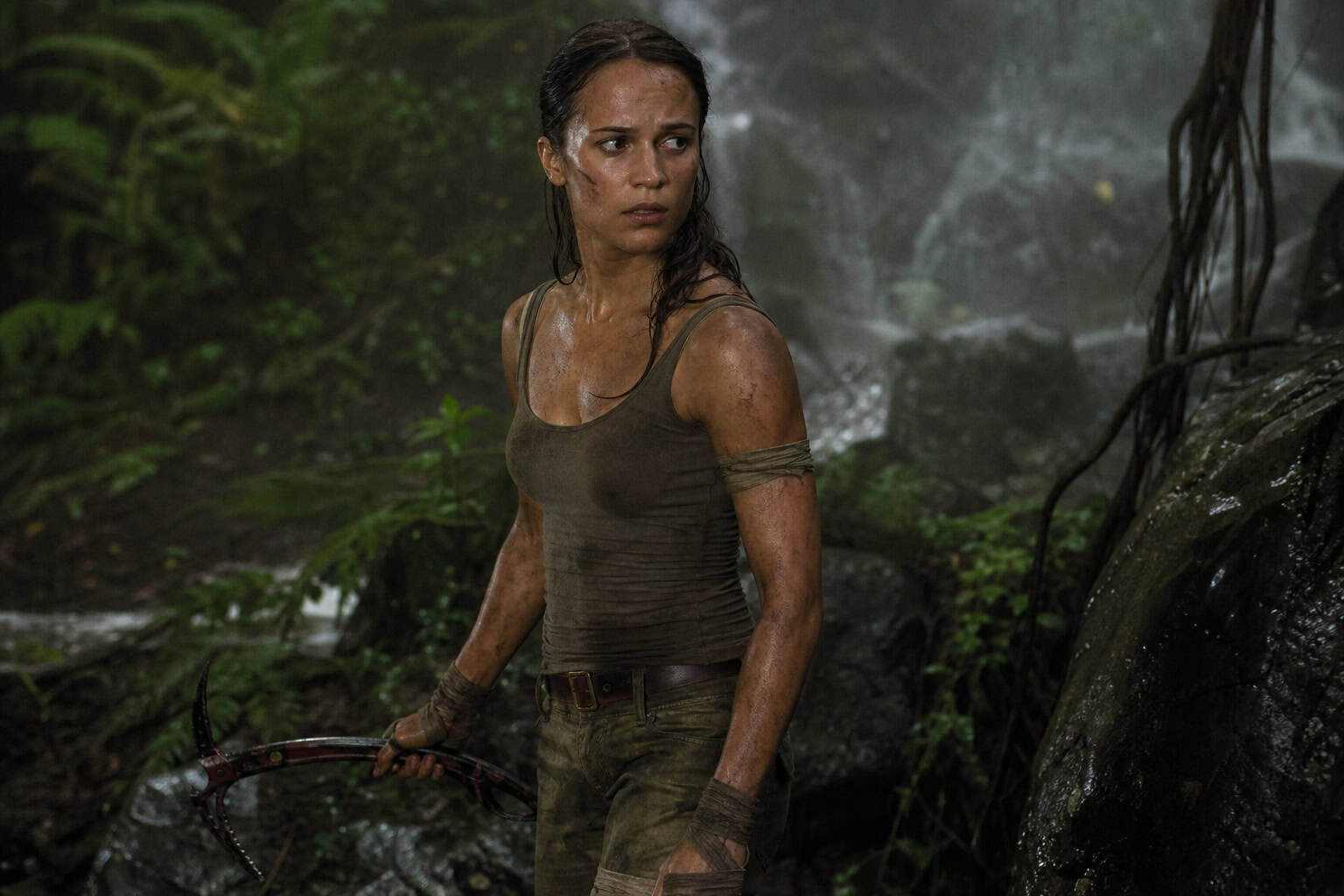 Lara Croft Game vs. Movie Outfits: A Side-by-Side Comparison 5 Alicia Vikander Lara Croft in grounded brown tank top and cargo pants from 2018 reboot.
