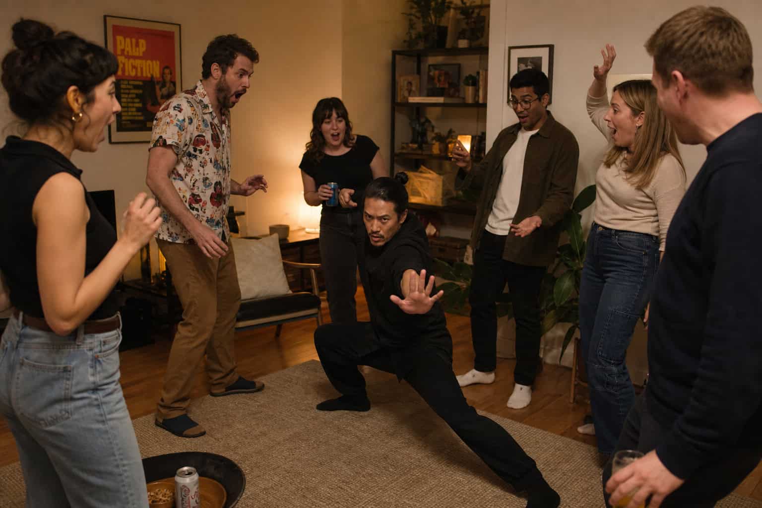 Adults playing Ninja in a living room circle, one striking a pose.