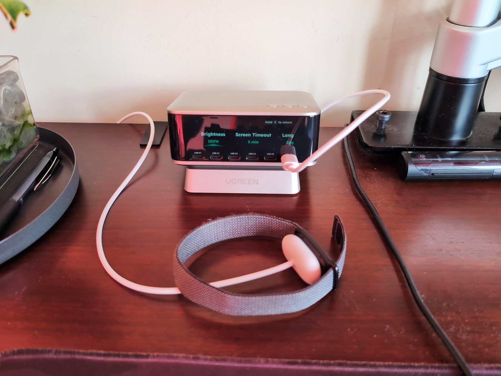 Close-up of UGREEN Nexode Pro 300W desktop charger with multiple ports and connected devices on a wooden desk.