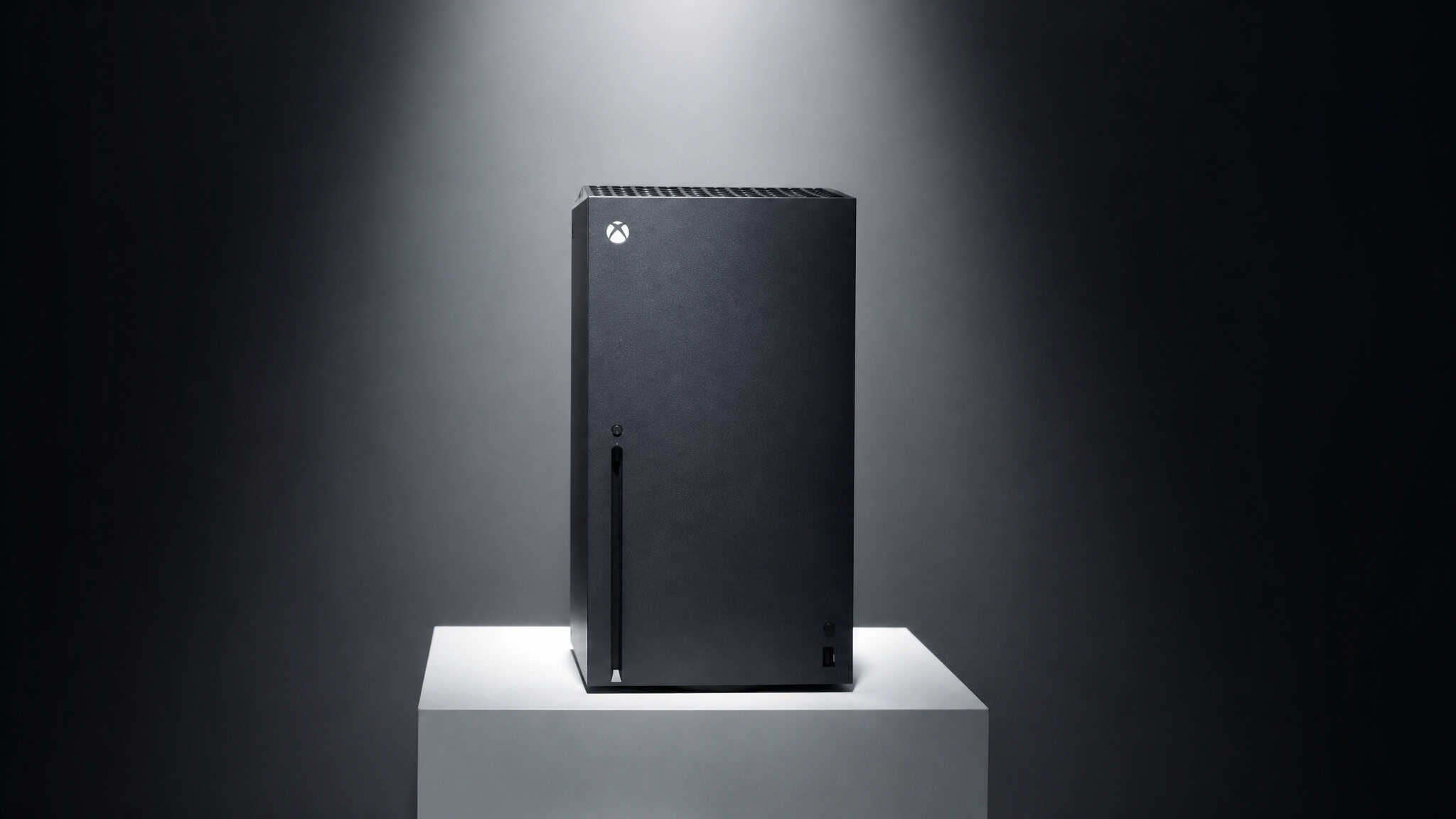 Xbox Series X gaming console on a white pedestal against a dark background, showcasing its sleek black design and vertical orientation.