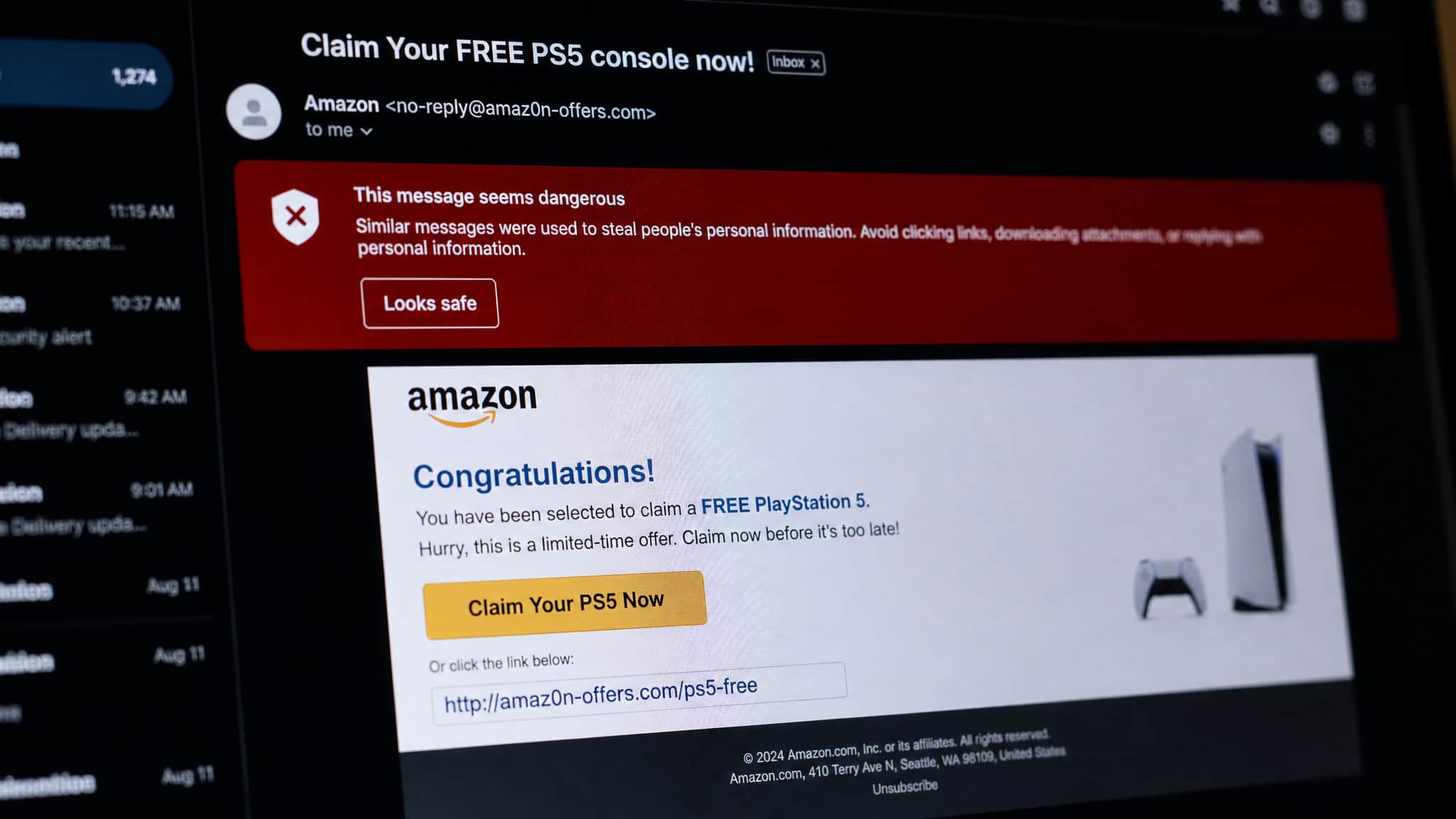 Computer screen showing a phishing email with a fake Amazon URL and 'Claim Your Free PS5' subject, with a red scam alert icon.