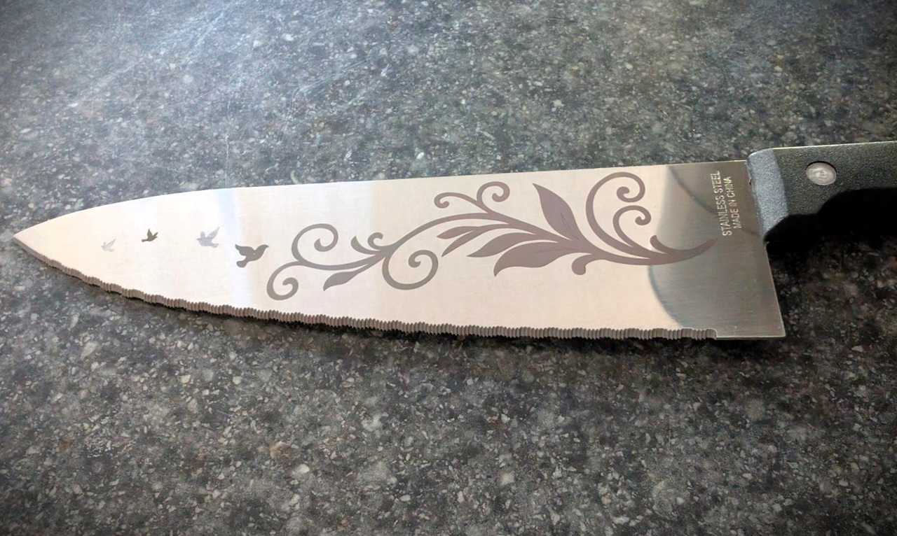 Is The WeCreat Lumos Flex The Best Metal Engraver? 5 Kitchen knife with decorative engraved floral pattern on blade, black handle, placed on dark countertop, suitable for culinary use and craftsmanship.
