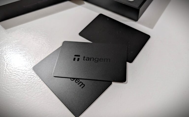 Close-up of Tangem wallet cards on a white surface, showing black and gray cards with the Tangem logo, used for secure digital currency storage.