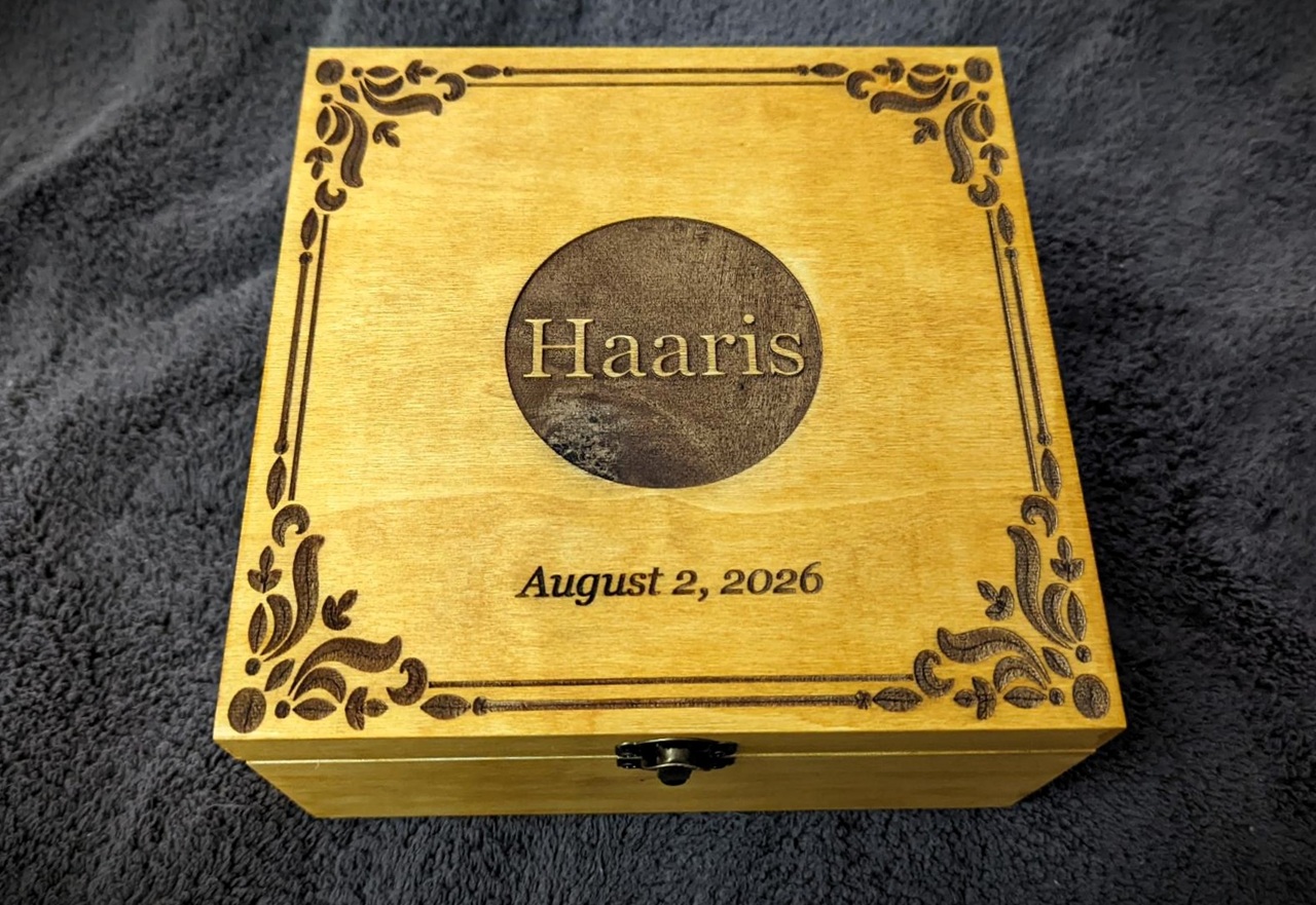 WeCreat Lumos Flex Review: Where the Metal Claims End and MOPA Begins 5 Decorative wooden box with the name Haaris and the date August 2, 2026, featuring ornate border designs, placed on a dark textured surface.