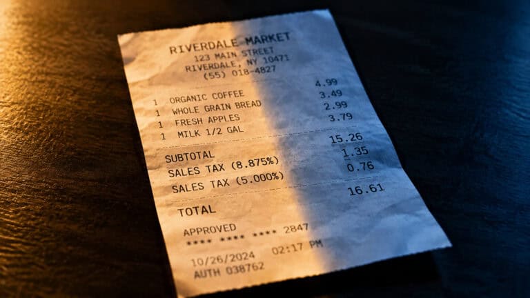 Close-up of a grocery store receipt from Riverdale Market listing items like organic coffee, bread, apples, and milk with prices and taxes.