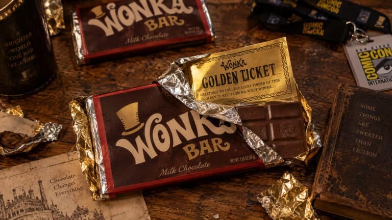 Close-up of a Wonka Bar with a Golden Ticket on top, surrounded by other chocolate bars and themed items, emphasizing nostalgic candy and movie memorabilia.
