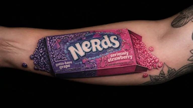 Close-up of a Nerds candy bar on a person's arm with colorful beads and tattoos, emphasizing the candy's packaging and vibrant colors.