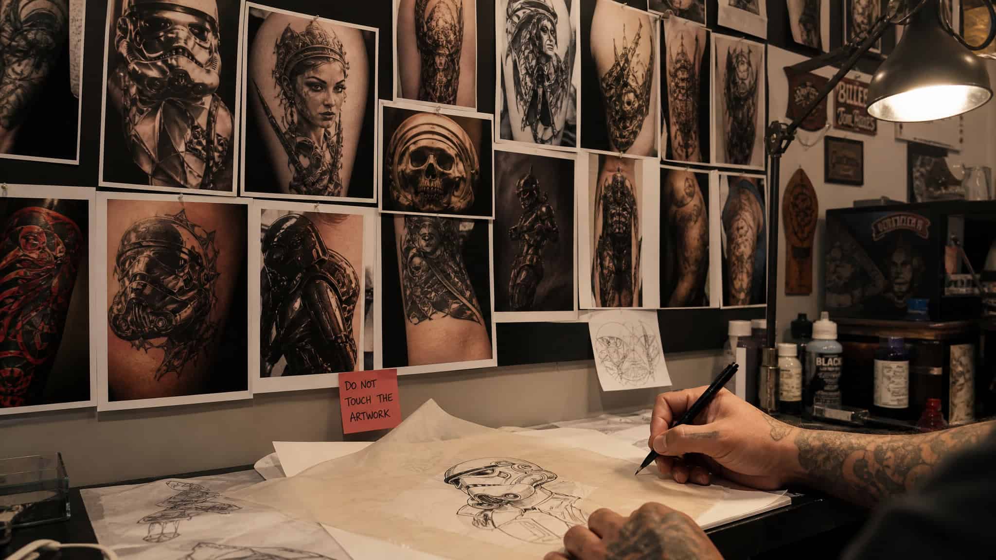 Star Wars Tattoo Ideas: 26 Artist-Credited Designs and Which Ones Age Well 116 Tattoo artist reviewing sci-fi portfolio prints while finding a Star Wars tattoo specialist