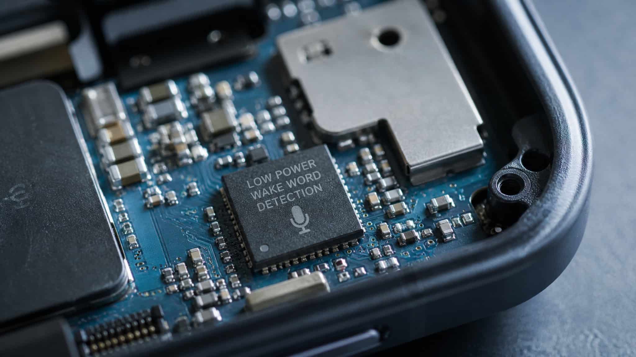 Macro view of a smartphone circuit board with a dedicated low-power wake-word detection chip highlighted