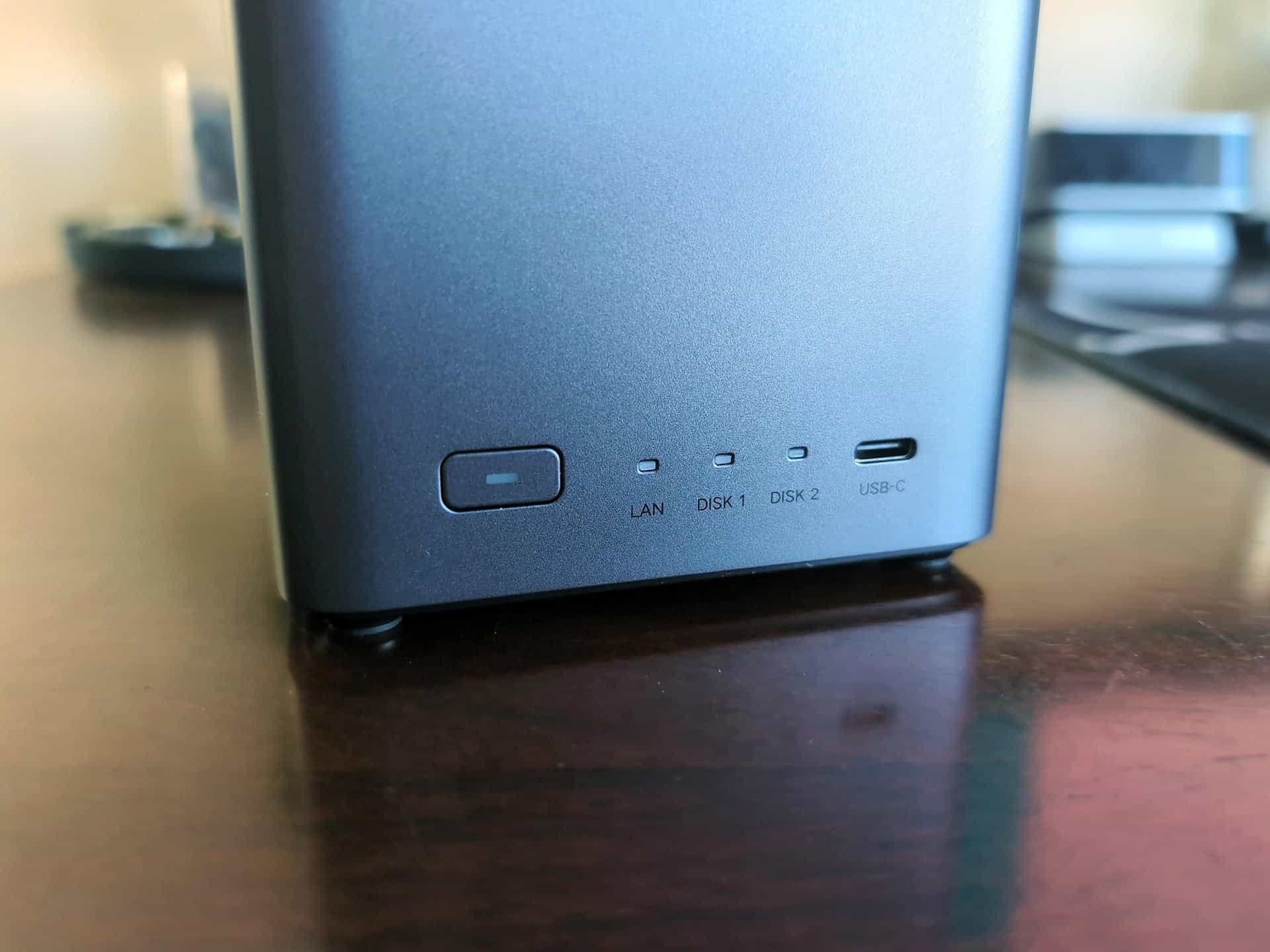 Ugreen DH2300 vs DXP2800 GT: Which Two-Bay NASync Should a First-Time Buyer Actually Get? 2 Close-up of a two-bay NAS device with LED indicators and USB-C port on a wooden surface, suitable for home or office data management.