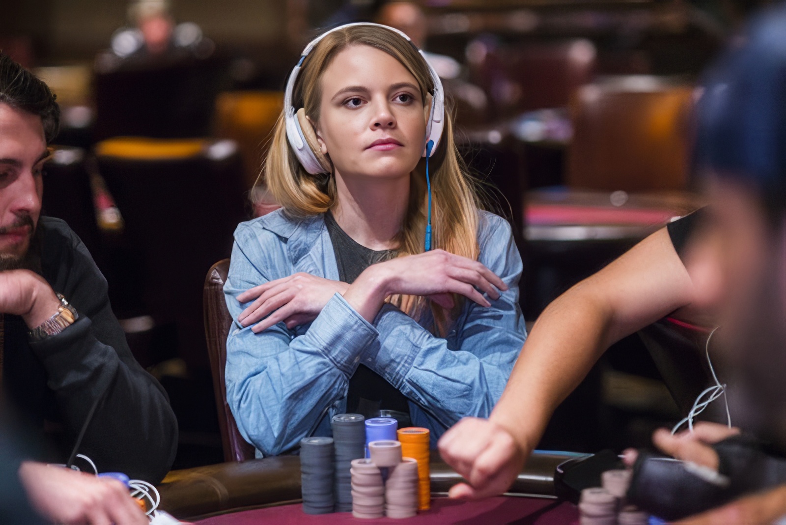 Cate Hall, a professional poker player, sitting at a poker table with chips, focused during a game, in a casino setting.